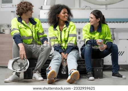 Break time. Group of diverse engineer people sitting together take a break and talking. Young multiracial woman and colleagues technician relax after job in factory. Manufacturing employee lifestyle. Royalty-Free Stock Photo #2332959621
