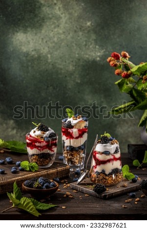 Homemade granola with greek yogurt, berries jam and fresh blackberries and blueberries in glasses. Healthy food, healthy eating concept.