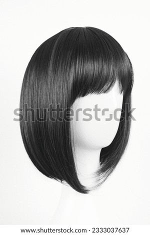 Natural looking black wig on white mannequin head. Medium length straight hair with bangs on the metal wig holder isolated on white background, side view Royalty-Free Stock Photo #2333037637