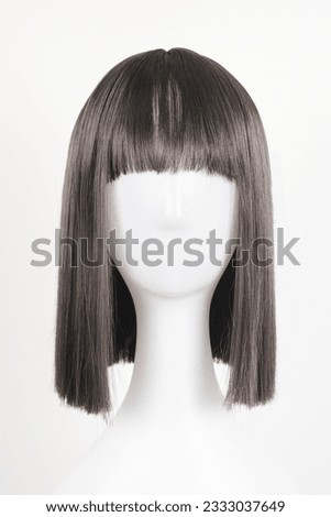 Natural looking black wig on white mannequin head. Medium length straight hair with bangs on the metal wig holder isolated on white background, front view Royalty-Free Stock Photo #2333037649