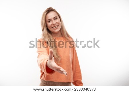 Portrait young woman chooses you isolated on white studio background, stretches her palm to the camera, come with me join us concept