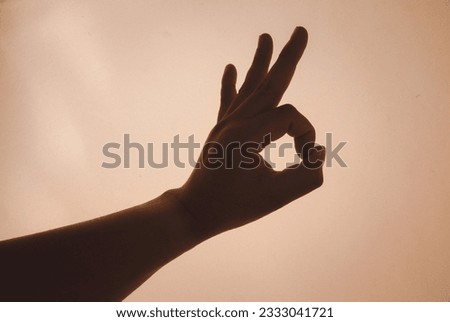 Male hand showing the ok gesture on a orange background. Okey hand sign.