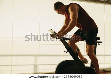 Young Caucasian man pushing himself to new limits on his state-of-the-art exercise bike, using the latest in fitness technology to achieve his health and fitness goals in the gym. Royalty-Free Stock Photo #2333049059