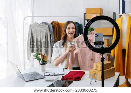 Beautiful woman describe selling clothes on camera live broadcast on social network at home, Online selling clothes on social media. Vlogger woman influencer, SME retail store owner. Royalty-Free Stock Photo #2333060275