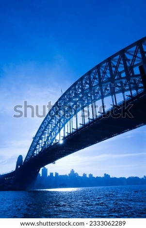Sydney Harbour Bridge at dusk with view of distant skyline and harbour in Sydney, Australia.