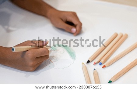 Children's hands are holding paint sticks on paper with various graphics and various colors.
