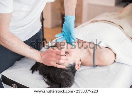 Osteopathic therapist doing treatment to Caucasian woman with jaw problem, mandibular alignment. Treatment to relieve pain and improve the patient's health conditions. Royalty-Free Stock Photo #2333079223