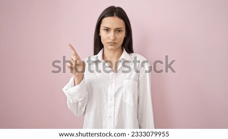 Young beautiful hispanic woman saying no with finger over isolated pink background Royalty-Free Stock Photo #2333079955