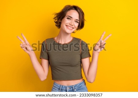 Photo of pleasant optimistic woman wear with bob hairstyle trendy t-shirt showing v-sign greetings isolated on yellow color background