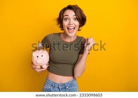 Photo of impressed lucky girl dressed khaki top rising fist collecting money isolated yellow color background