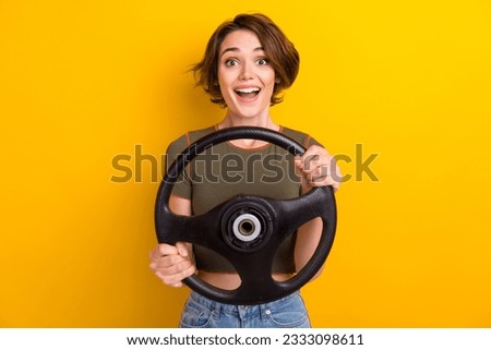 Photo of satisfied impressed nice girl dressed khaki t-shirt holding steering wheel buy new car isolated on yellow color background