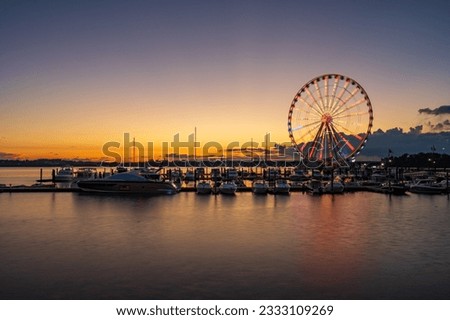 Illuminated ferris wheel at National Harbor near the nation capital of Washington DC at sunset with marina in the foreground Royalty-Free Stock Photo #2333109269