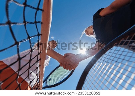Two female tennis players shaking hands with smiles on a sunny day, exuding sportsmanship and friendship after a competitive match. Royalty-Free Stock Photo #2333128061