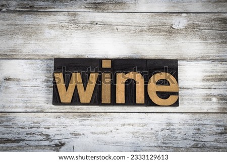 The word -wine- written in wooden letterpress type on a white washed old wooden boards background.