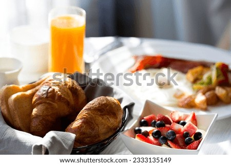 delicious healthy fruit bowl for breakfast with orange juice and pastries in the background, in-room dining at the hotel