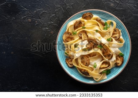 Mushroom pasta, pappardelle with cream sauce and parsley, shot from above on a black stone background, with a place for text Royalty-Free Stock Photo #2333135353