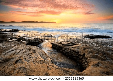 Spectacular sunrise beautiful skies and light from the rocky coastline near Pearl Beach, Australia