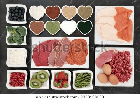 Large body building health food selection with meat, fish, supplement powders, dairy, fruit and vegetables on porcelain plates.
