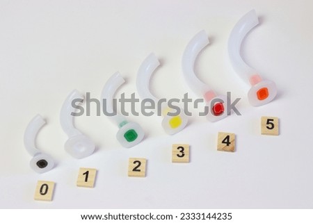 Oropharyngeal airway cannula in a white surface aligned by the size of each cannula. Small to big size. 0 to 5 size of a guedel cannula  Royalty-Free Stock Photo #2333144235
