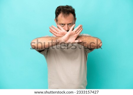 Middle age caucasian man isolated on blue background making stop gesture with her hand to stop an act