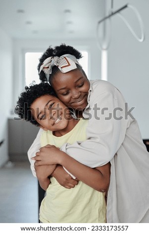 Vertical image of happy African American mom embracing her cute son