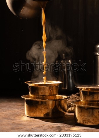 South Indian traditional filter coffee in a traditional brass dabra coffee set on a rustic low light background- selective focus.  Royalty-Free Stock Photo #2333195123
