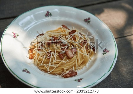 Close up picture on vintage rustic plate with spagetti carbonara. Traditional recipe from italian cuisine consist from pasta, roasted italian bacon and sauce from fresh egg yolks and parmesan cheese.
