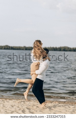 Guy and girl are hugging on wet beach near sea in summer