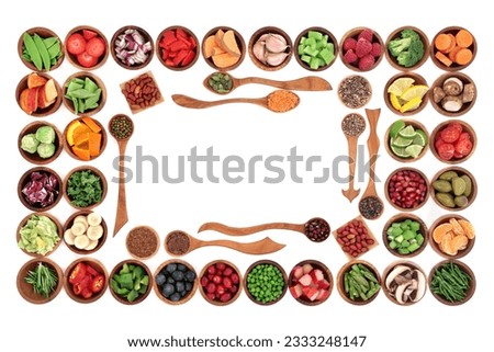 Paleo diet health and super food of fruit, herbs, vegetables, nuts and seeds in wooden bowls forming an abstract border over white background. High in vitamins, antioxidants, minerals and anthocyanins
