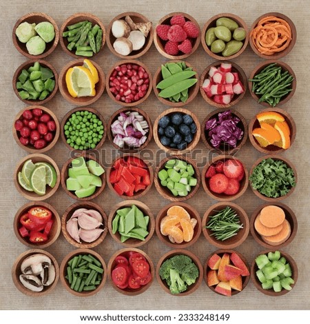 Super food sampler for paleolithic diet with fresh vegetables and fruit in wooden bowls over brown paper background. High in vitamins, antioxidants, minerals and anthocyanins. Royalty-Free Stock Photo #2333248149