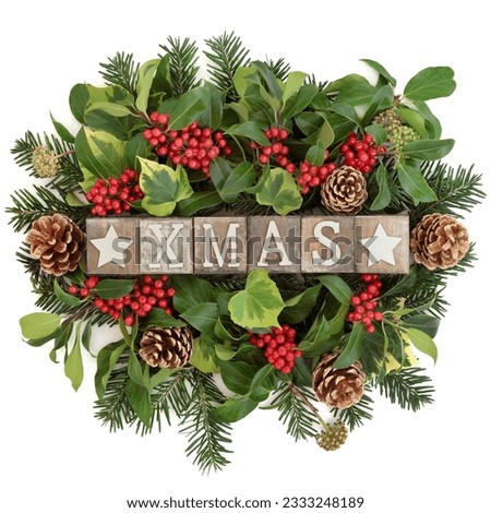 Christmas decoration with xmas sign in old wooden blocks, holly, ivy, gold pine cones and fir leaf sprigs over white background.