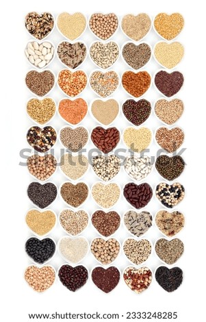 Grain food and vegetable pulses in heart shaped porcelain bowls over white background.