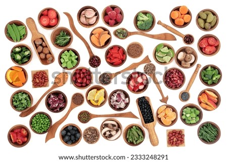 Health and super food of fruit, nuts, seeds and vegetables in wooden bowls and spoons over white background, high in vitamins, antioxidants, anthocyanins and minerals.