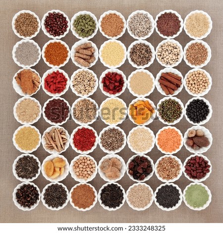 Large dried superfood selection in porcelain china bowls forming an abstract background over hessian. High in antioxidants, vitamin, minerals and dietary fiber.