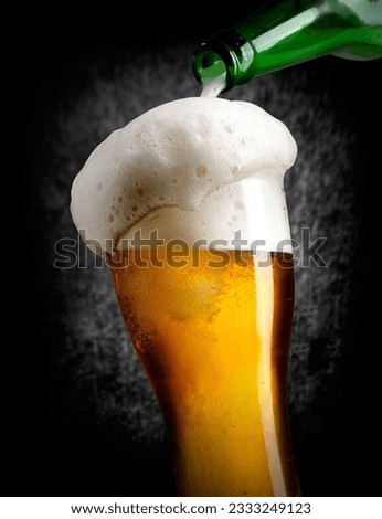 Beer pouring into glass on black background