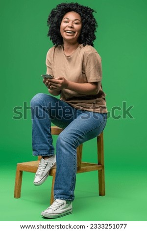 Excited young woman sitting on the chair with a phone in hands
