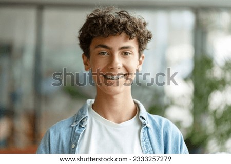 Closeup portrait of smiling smart curly haired school boy wearing braces on teeth looking at camera. Education concept  Royalty-Free Stock Photo #2333257279