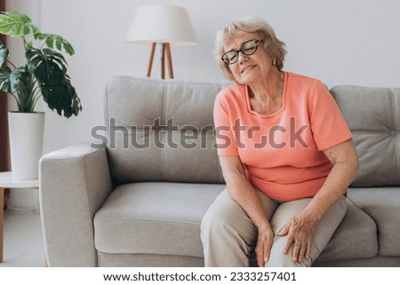 Senior woman suffering from pain in knee at home Royalty-Free Stock Photo #2333257401