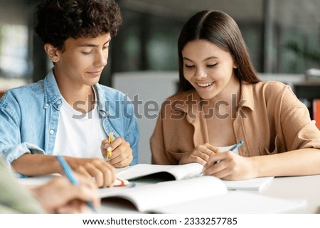 Portrait of school girl and boy studying together, learning language, exam preparation sitting in modern classroom. Back to school, lesson, education concept  Royalty-Free Stock Photo #2333257785