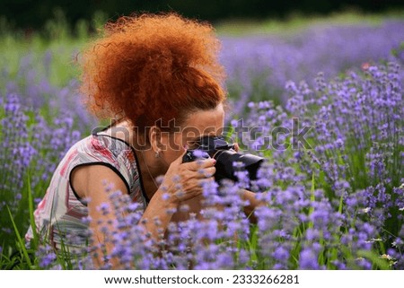 Woman nature photographer with her camer in a  lavender field shooting pictures