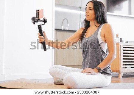 Young Latin woman making a sports stream with her mobile phone and a digital stabilizer at home for her networks