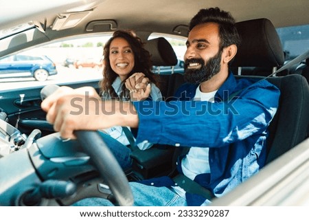 Happy loving arab couple holding hands while sitting in new comfortable auto, middle eastern guy having car trip with his girlfriend, summer vacation concept Royalty-Free Stock Photo #2333290287