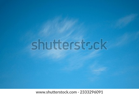 Blue sky with fluffy white clouds moved by the wind in horizontal background