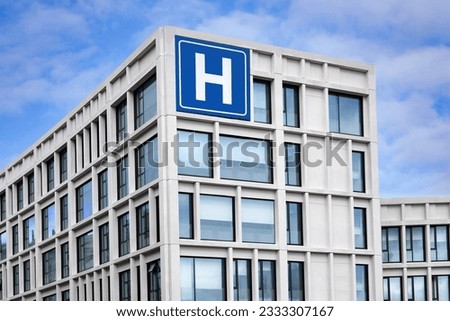 Modern concrete building with large blue H sign for hospital