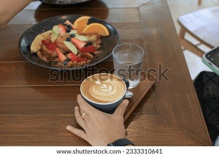 Coffee latte on wooden table in the breakfast morning. Warm, light atmosphere. Relaxing in a coffee shop.