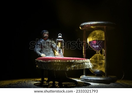 Time concept. Man sitting on table with hourglass. Abstract hourglasses with smoke and lights on a dark background. Surreal decorated picture