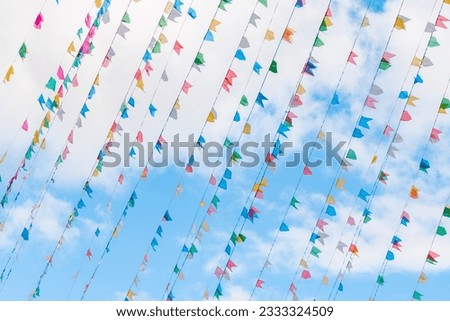 Photograph of colorful party flags fluttering, with blue sky in the background.