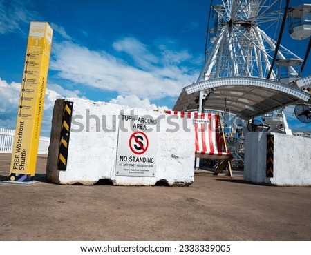 A large white painted concrete no standing sign at the Darwin harbor protecting a playground in the background.