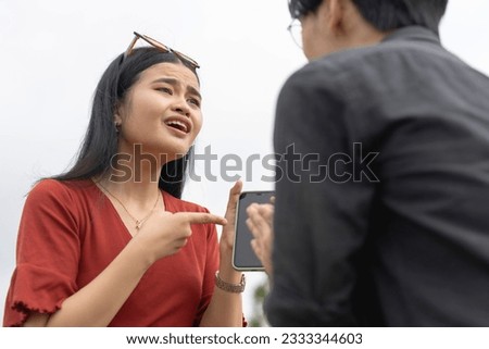 A young asian woman breaks down after catching her boyfriend sending illicit messages with another woman. Infidelity and crisis in a young relationship. Royalty-Free Stock Photo #2333344603