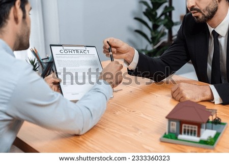 Real estate agent handing pen to client for signature on house loan contract paper. Persuasive broker try to ensure successful deal by giving pen to customer and encourage buyer to sign paper. Fervent